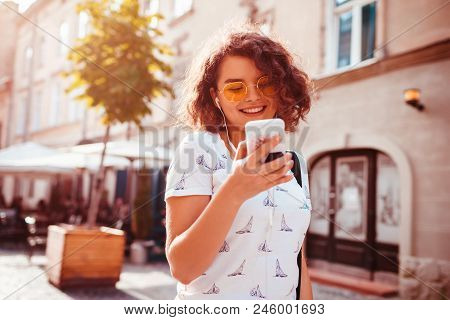 Beautiful Young Girl Using Smart Phone And Listening To The Music Walking On Street. Happy Woman Dan
