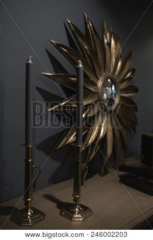 Two Blue Candles Stand On A Wooden Table With A Mirror