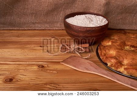 Apricot Pie And A Bowl With Flour And Other Ingredients On Wooden Table