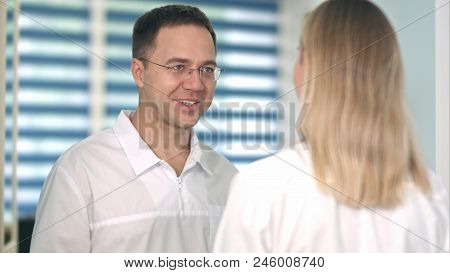Smiling Male Doctor In Glasses Talking To Female Nurse. Close
