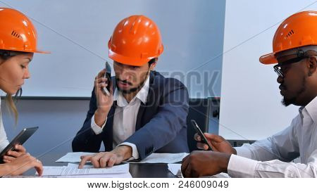 Tree Colleagues In Helmets Discuss Constraction Plan, Using Digital Tablet