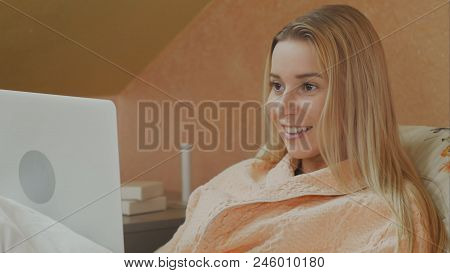 Focused Woman Using Laptop Having Video Chat While Lying In