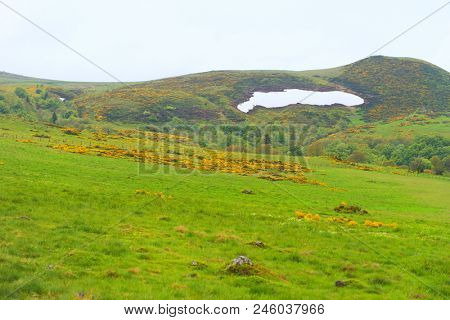Green landscape with eternal snow in French Auvergne Massif du Sancy Puy de Dome