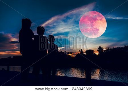 Silhouette Of Mother And Children Looking At Red Super Moon Or Blood Moon On Colorful Sky With Cloud