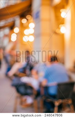 Blurred Background With Group Of Peolple Sitting At The Cafe Veranda Outside.