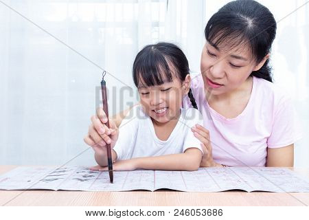 Asian Chinese Mother Teaching Daughter Practice Chinese Calligraphy At Home