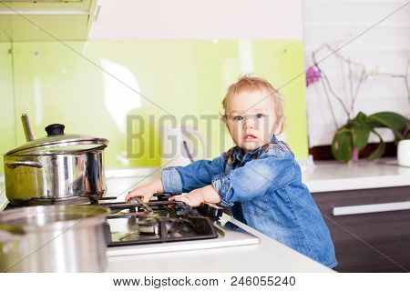 Cute Boy Playing With The Gas Stove By Himself. Small Boy Left Alone In The Kitchen, Playing With Th