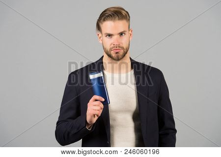 Confident In Hair Care Product. Man Stylish Hairstyle Holds Bottle Hygienic Product Grey Background.