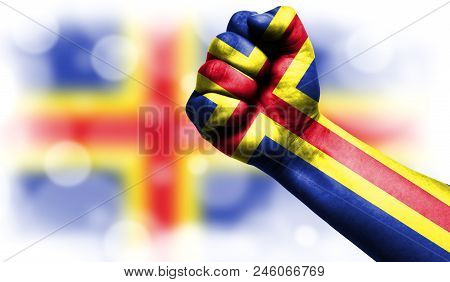 Flag Of Aland Drawn On Male Fist, Strength, Power, Concept Of Conflict. On A Blurred Background With