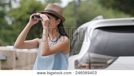 Woman travel with her car and looking though the binocular and enjoy natural landscape 