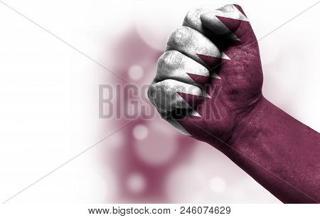 Flag Of Qatar Painted On Male Fist, Strength, Power, Concept Of Conflict. On A Blurred Background Wi