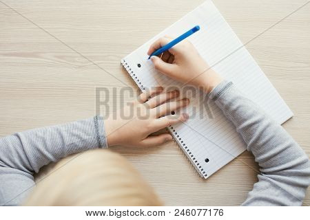 Kid Holding Pen And Writing In Notebook. Close Up, Top View.