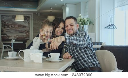 Beautiful Young Family Taking Selfie On Smartfone While Enjoying Their
