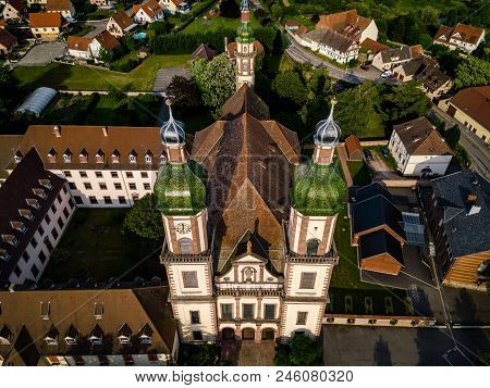 Soaring Majestic Church Saint Maurice In Little French Village Ebersmunster. Aerial Drone View.