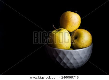 Bowl Of Yellow Apples. On Black Background. A