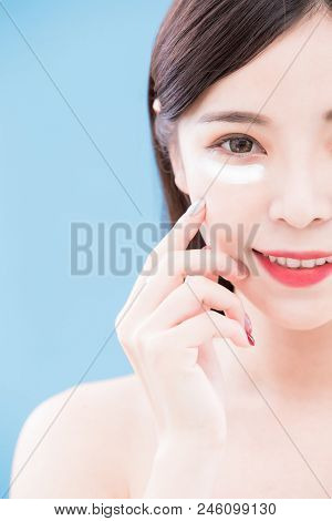 Woman Use Eye Scream On Her Face With Blue Background