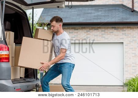 Strenuous Young Man Moving Boxes From Car Into New House