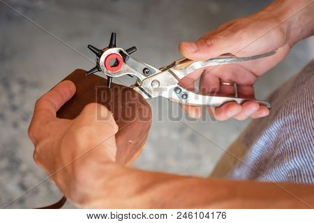 Making Holes With Puncher In Leather Workshop. Male Hands With Eyelet Puncher Working With Piece Of 