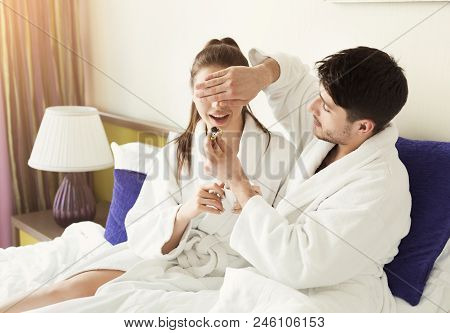 Loving Couple Having A Lazy Morning Breakfast In Comfortable Bed. Husband Feeding Wife