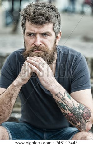 Man With Beard And Mustache Sits Outdoor. Bearded Man On Serious Face Looks Sad And Troubled, Suffer