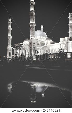 Lit City Mosque With Reflection In The Surface Of Puddle On The Pavement.