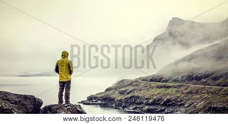 traveller with yellow raincoat in faroe islands