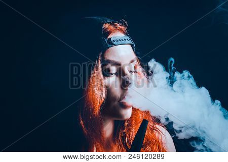 Red-haired Sexy Girl Dressed In Swimsuit And Cap Smoking A Hookah. Toned Image. Concept Of Pleasant 