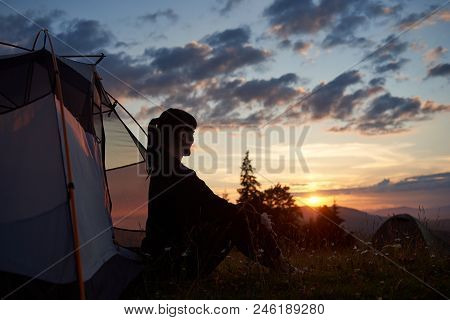 Profile Silhouette Of Young Woman Sitting In Tent In Grass And Fieldflowers On Top Of Mountain With 