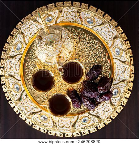 Traditional Golden Arabic Coffee Set With Dallah, Three Cups Of Tea And Dates. Dark Background. Squa