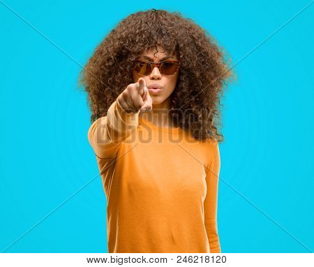 African american woman wearing an orage sweater pointing with finger to the camera and to you, hand sign, positive and confident gesture from the front