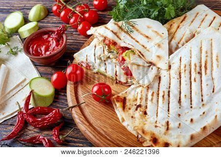 Close-up Of Grilled Flatbread Wraps Stuffed With Tomato And Zucchini Slices, Greens And Grated Mozza