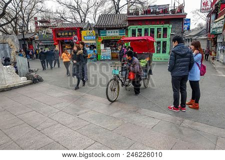 Beijing, China - March 12, 2016: Tourists In A Rickshaw In A Hutong, Ancient Hutongs Are Formed By A