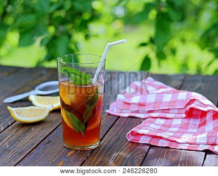Cool Drink, Cold Black Tea With Lemon, Mint And Ice In Tall Glasses On A Wooden Background. Summer C