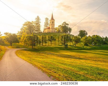 Small Church In The Middle Of Lush Green Spring Landscape On Sunny Day. St. Peter And Pauls Church A