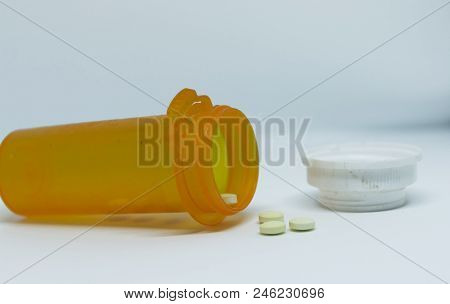 A Prescription Pill Bottle Has Fallen And He Drugs Are Falling Our Of It.