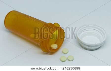 A Prescription Pill Bottle Of Oxycodone Is Laying On Its Side With Pills Coming Out On To The Ground