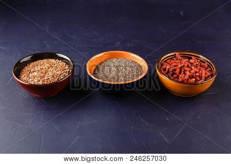 Super Foods - Chia Seeds, Flax Seeds And Goji Berries In Three Ceramic Bowls