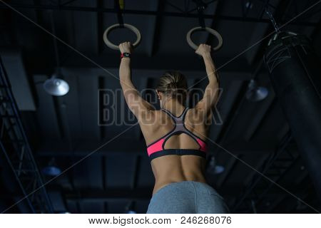 Young Woman Doing A Pullup Ongymnastic Rings, In The Gym.