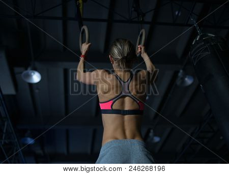 Young Woman Doing A Pullup Ongymnastic Rings, In The Gym.