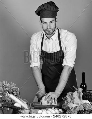 Man In Cook Hat And Apron Cuts Cabbage. Cook Works In Kitchen Near Table With Vegetables And Tools. 
