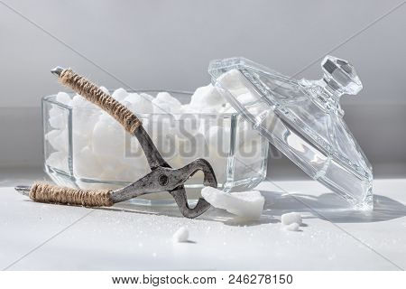 Old Nippers For Splitting Lump Sugar And Glass Sugar Bowl With Lid On Light Background