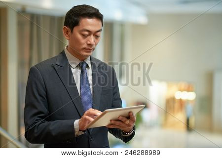 Vietnamese Business Executive Checking Information On Tablet Computer