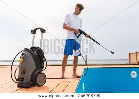 A Man Is Cleaning A Swimming Pool With The Hepl Of A Vacuum Cleaner.