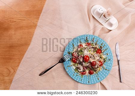 A Plate With Caesar Salad Is Served On The Table, Covered With The Beige Table Cloth.