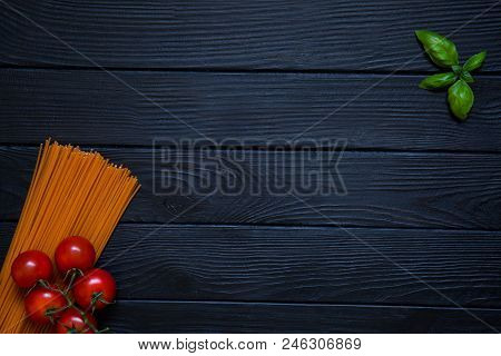 Tomato Orange Spaghetti With Fresh Cherries And Basil Leaf On Black Wooden Background. Italian Cuisi