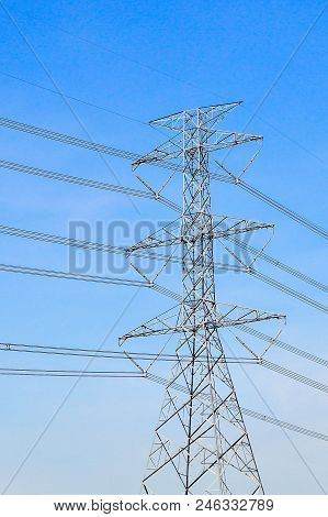 High Voltage Pole Transmission Tower With Bright Blue Day.