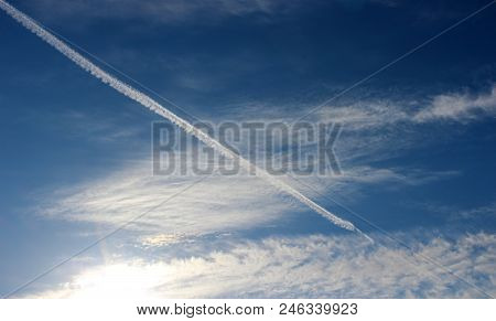 Deep Blue Skies With Puffy Clouds And Streaks Of White From 
Jet Liners Flying Overhead.