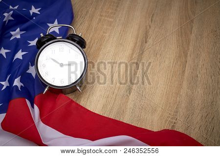 National flag of America and black alarm clock on old wooden background