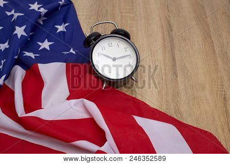 National flag of America and black alarm clock on old wooden background