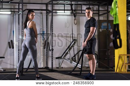 young fit sports couple working out in functional training gym doing  battle ropes cross fitness exercise